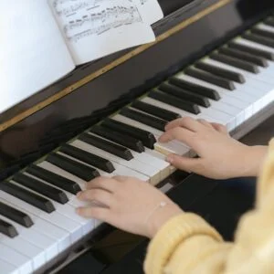 Close-up of a woman playing piano with sheet music, capturing musical talent and concentration.