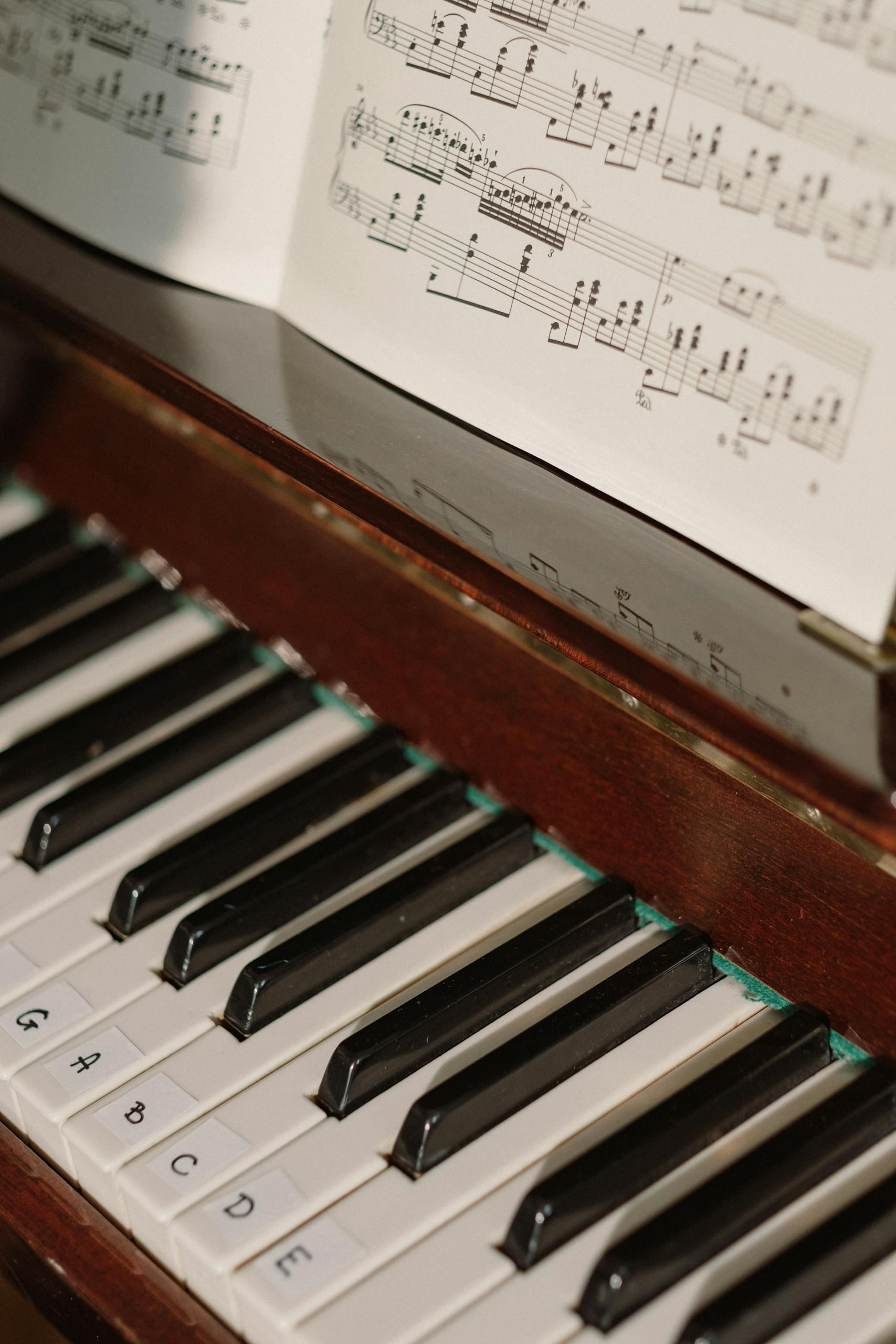 Detailed view of piano keys alongside a sheet music piece, capturing a musical ambiance.