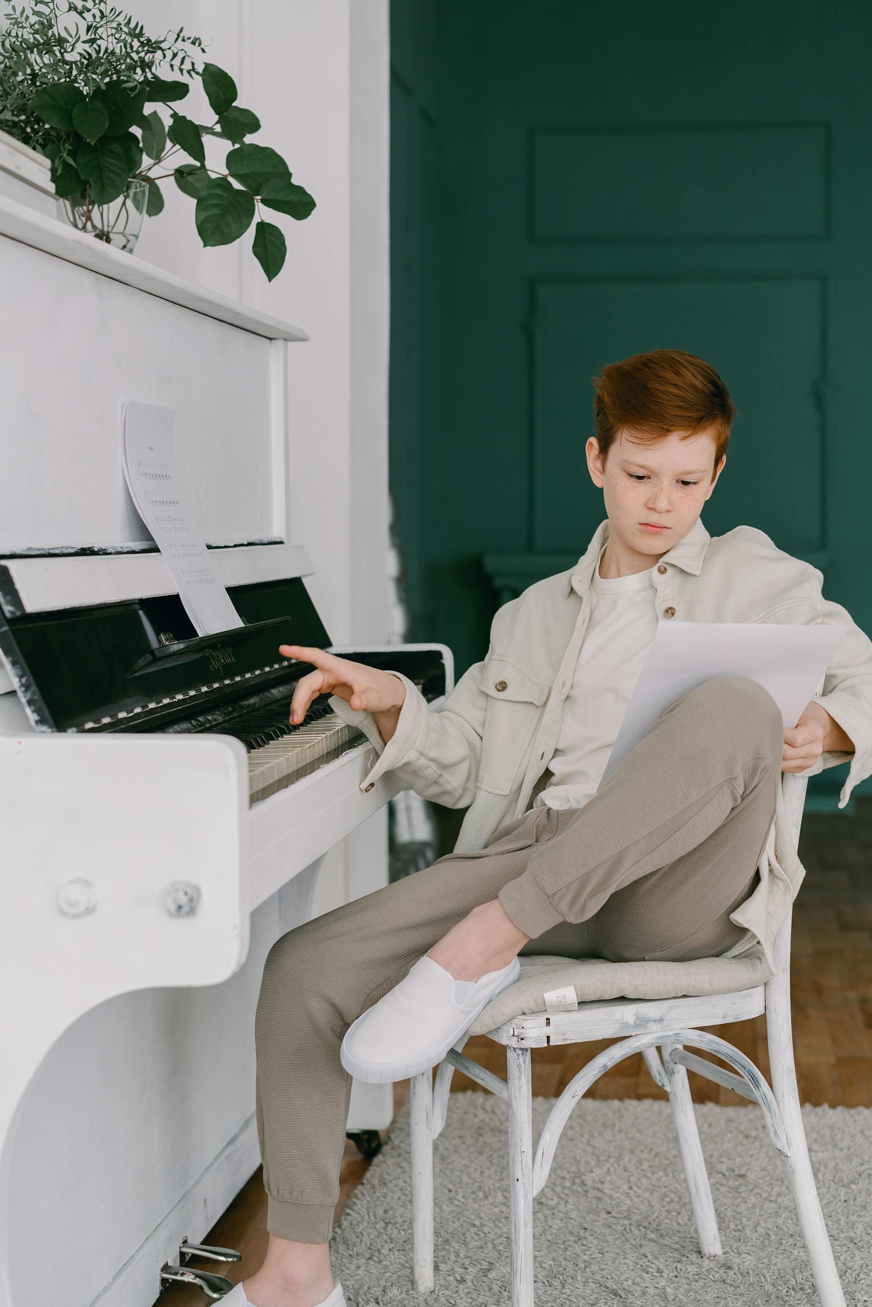 Young boy practicing piano and reading music indoors, embracing musical education.